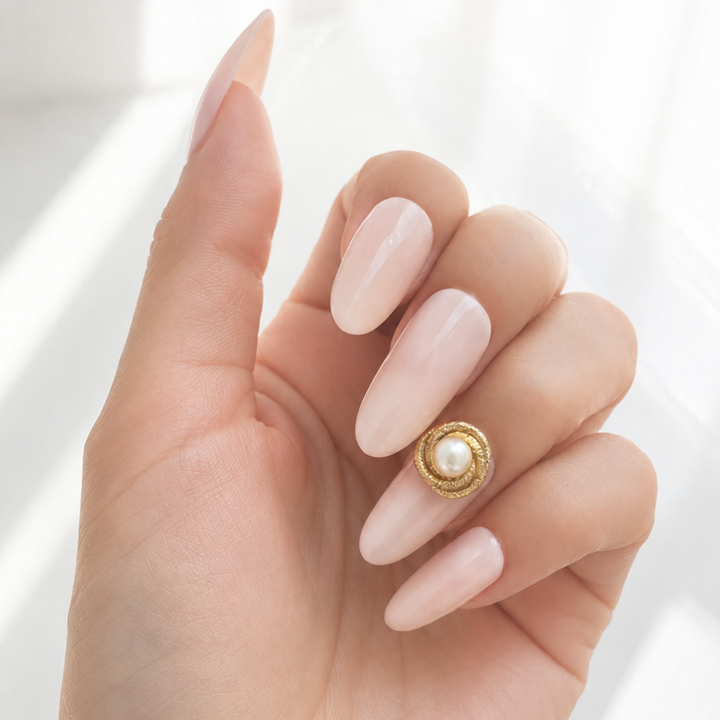Signature Line Frost brass nail accessory with pearl worn on a pink beige nail.